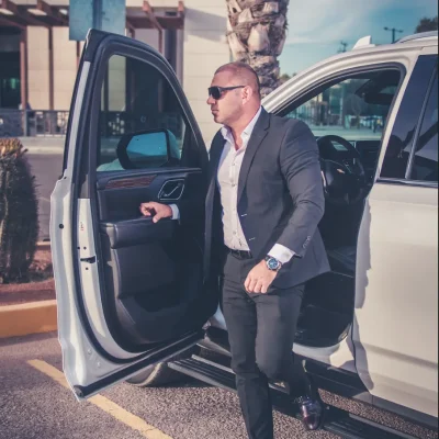 Ejecutivo descendiendo de una camioneta de seguridad privada en un área corporativa.