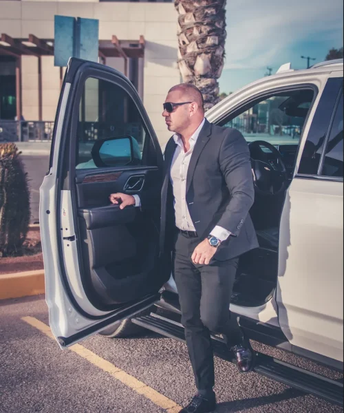 Ejecutivo descendiendo de una camioneta de seguridad privada en un área corporativa.