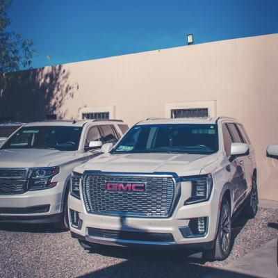 Vehículo GMC Yukon blindado color blanco estacionado junto a otra camioneta, parte de un servicio de seguridad privada.
